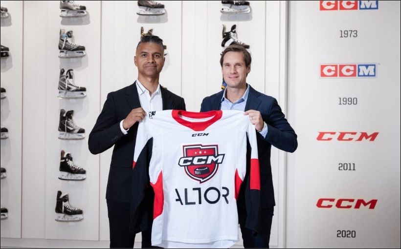 Two men hold up a jersey bearing the words CCM and Altor.