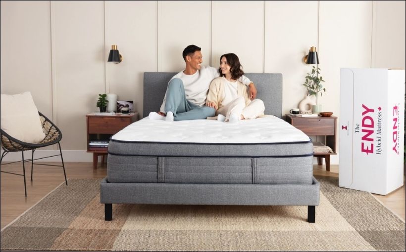 Photo of man and woman sitting on a mattress.