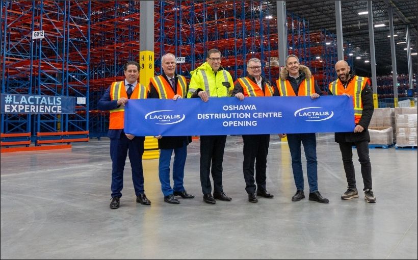 Photo of men holding a sign in a warehouse.