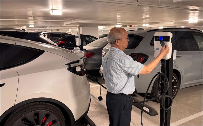 Photo of a man at an EV charger, by Environmental Communications Options.