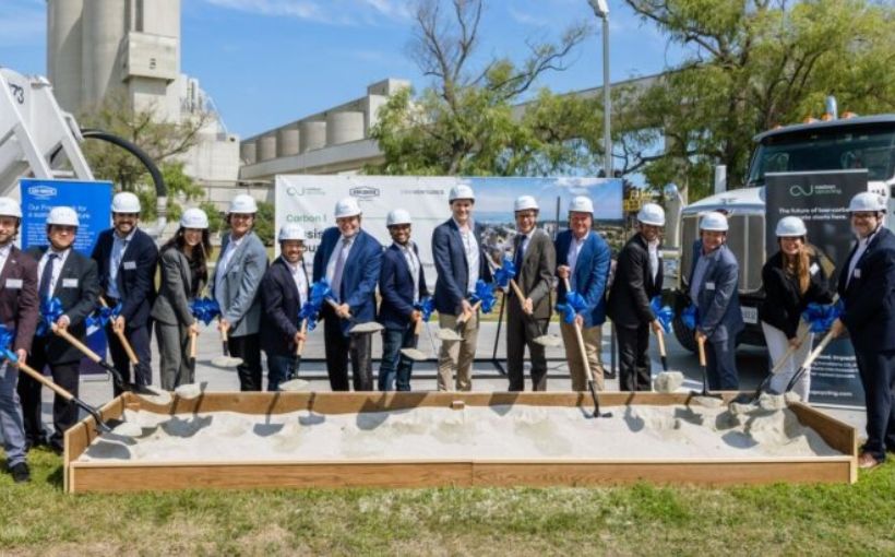 Photo of people in hardhats holding shovels full of dirt at a groundbreaking ceremony.