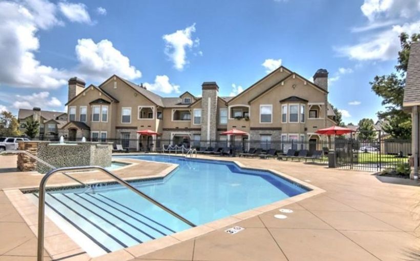 Photo of a pool in front of a rental-housing complex.